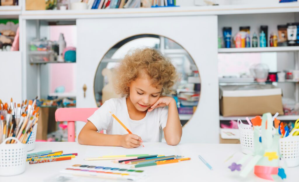 Cute little blonde preschooler girl draws at home