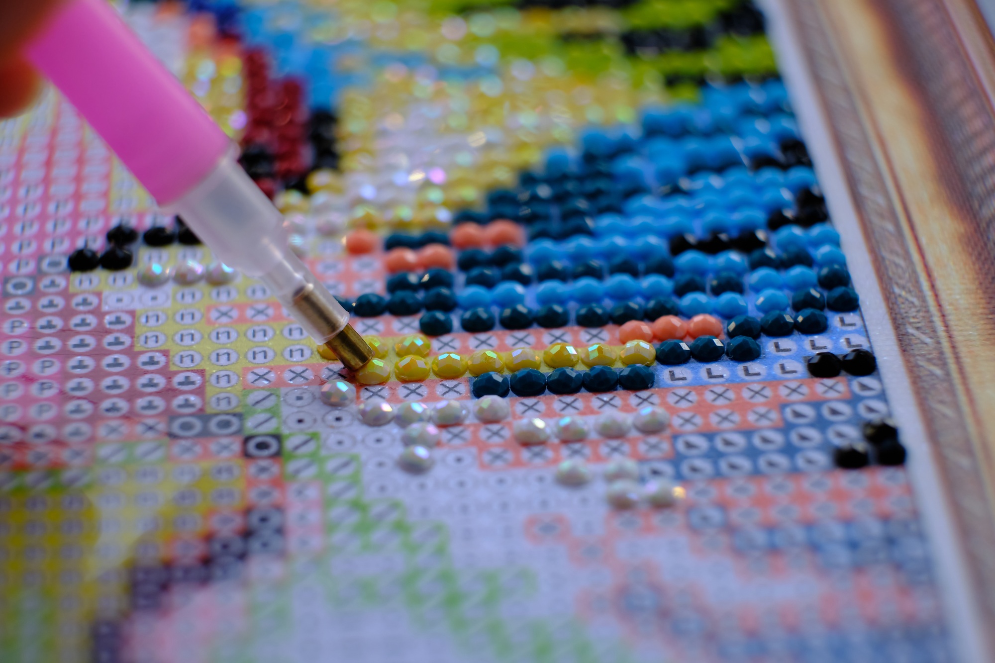 Diamond painting with pen closeup. art therapy concept. Laying out a diamond mosaic improves a woman