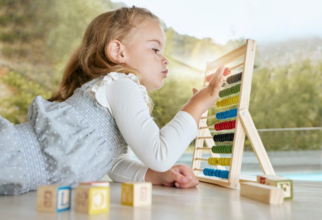 Education, abacus and girl learning math with a color tool while counting on the floor in th home l