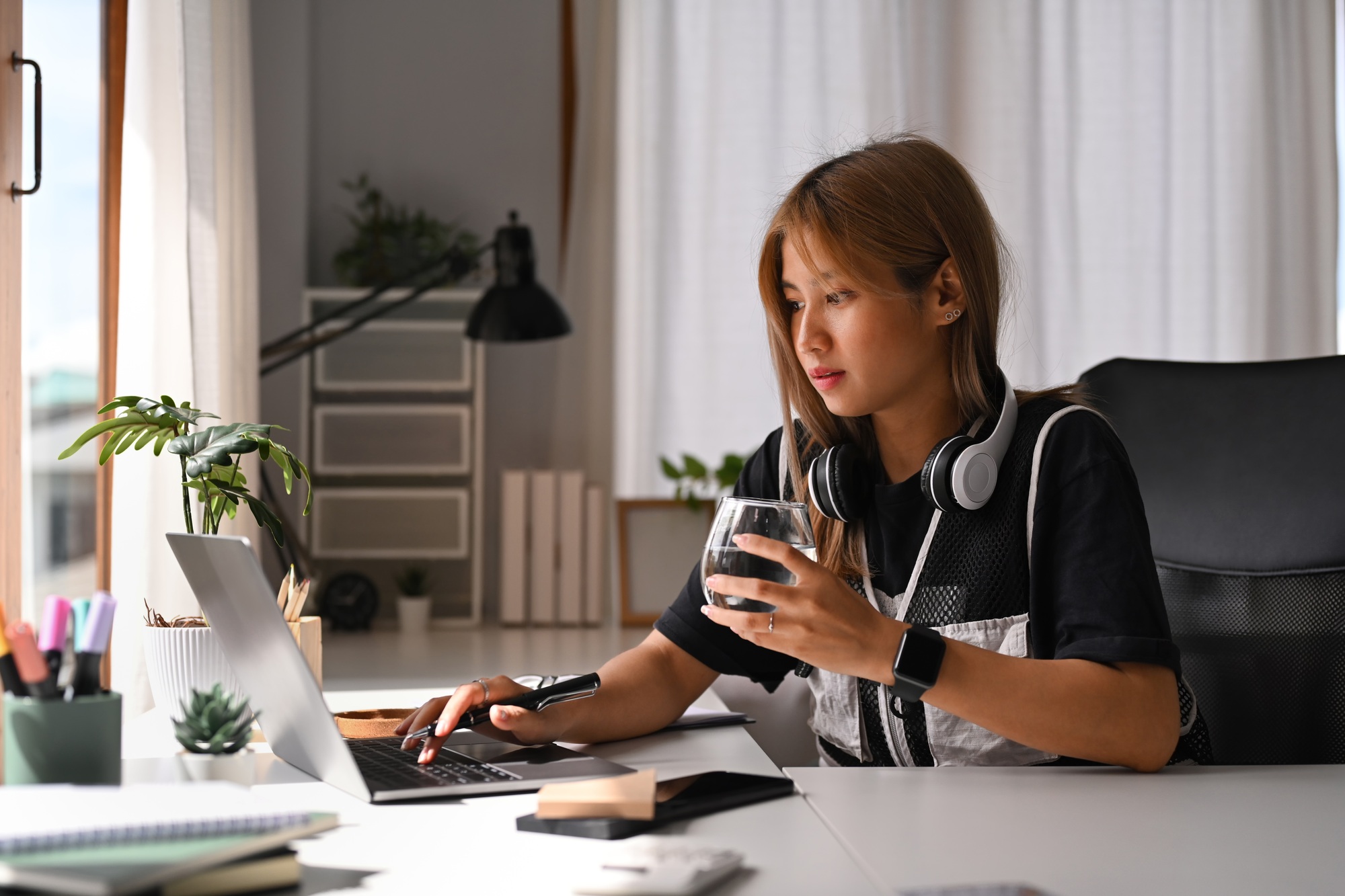 Beautiful young female freelancer drinking coffee and working online or searching online.