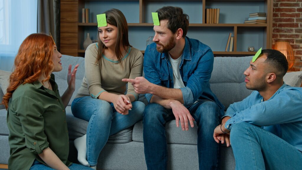 Group of multiethnic friends play charades game at home happy laughing diverse ethnic men and women
