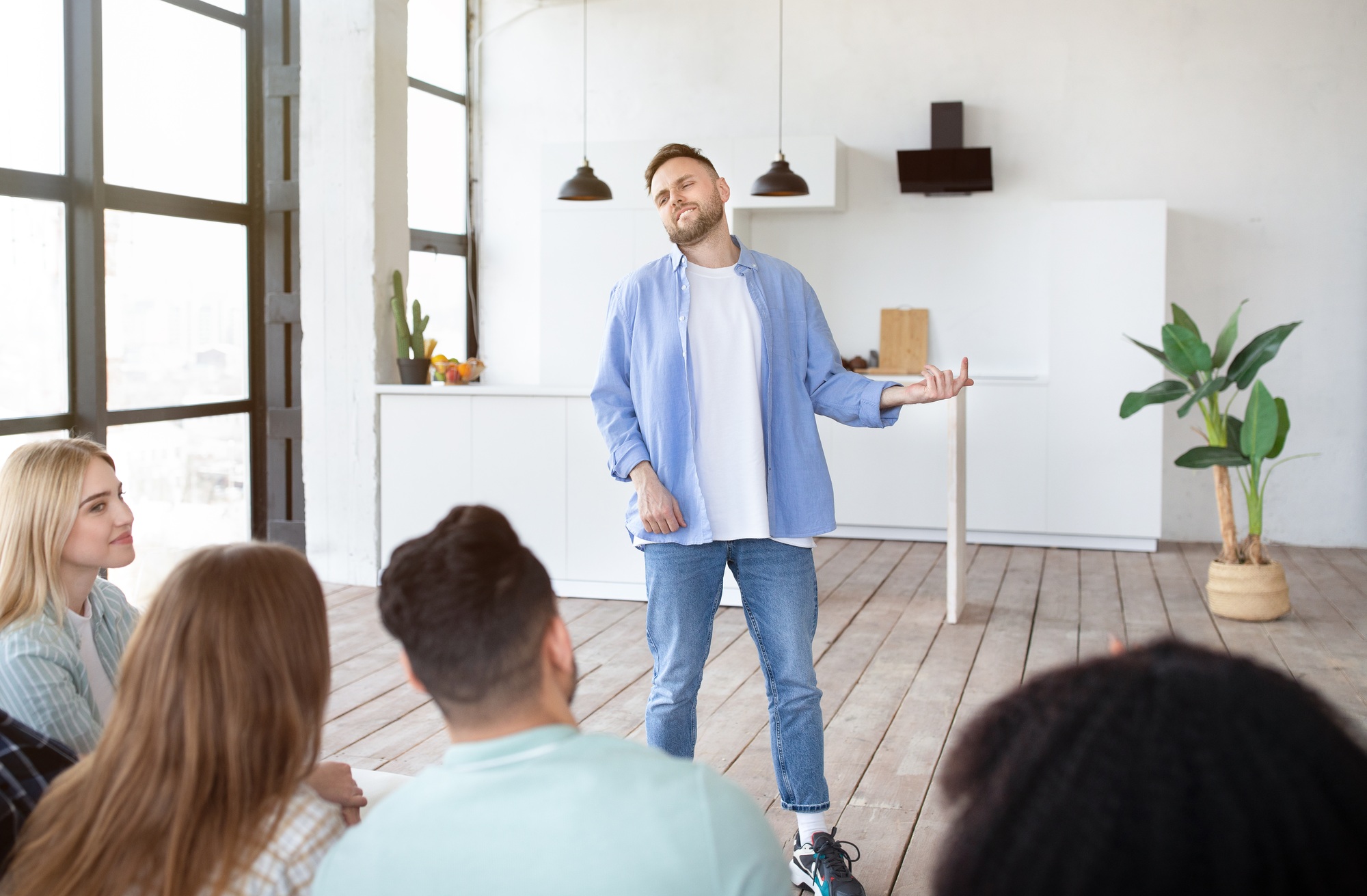 Positive young guy playing charades with his interracial friends, enjoying fun game
