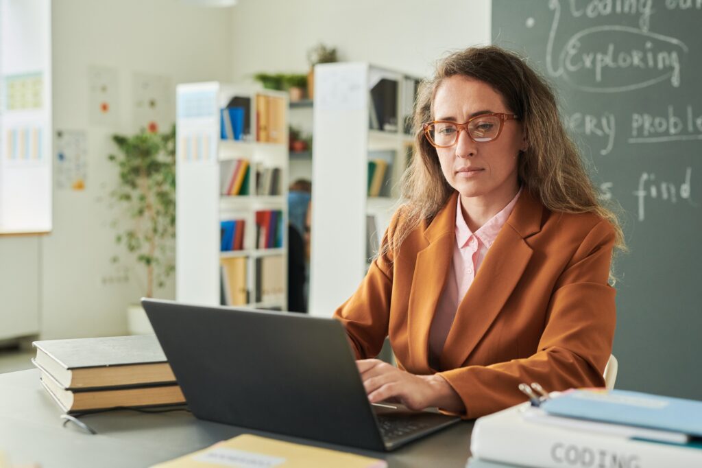 Teacher using Laptop at Desk
