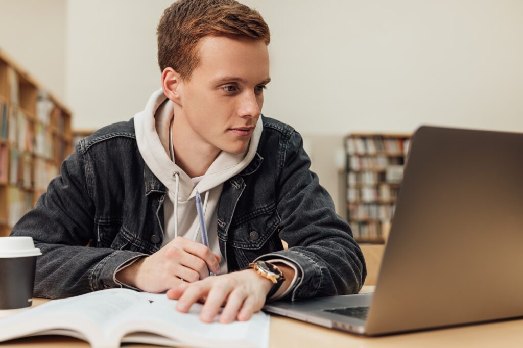 University student with ginger hair sitting at a desk.