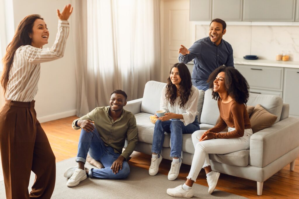 Young international students playing charades in the living room